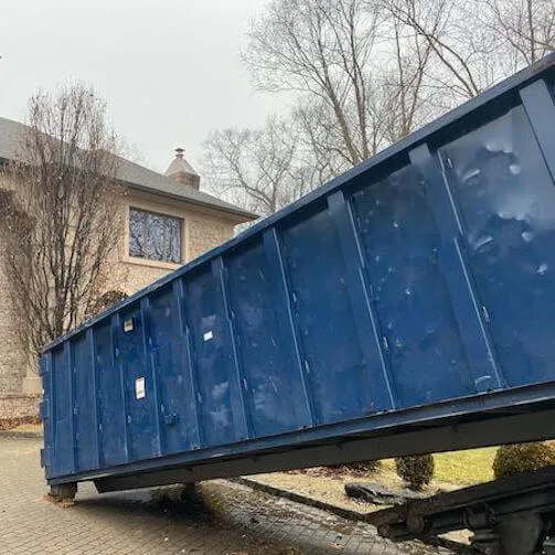 Large roll off bin being placed on driveway of home