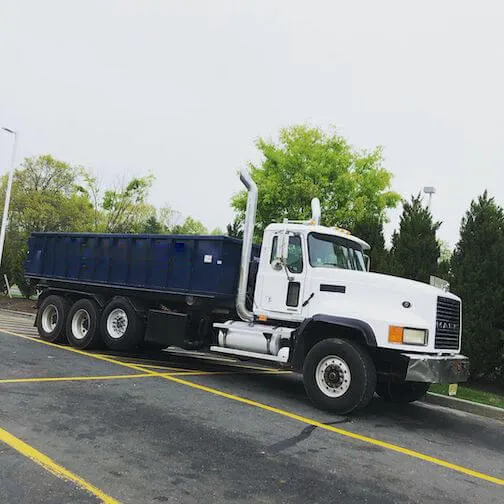Image of truck with blue bin in front of trees