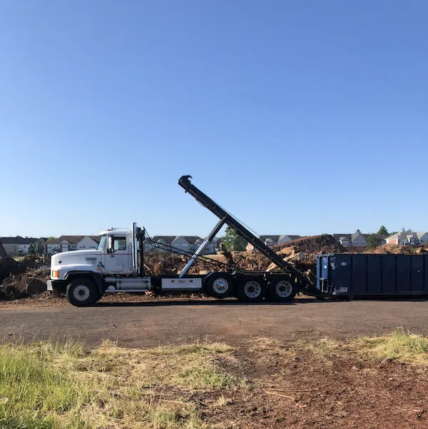 Dumpster truck offloading roll off bin in Orlando FL