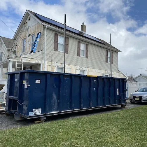 Large blue dumpster outside of house under construction