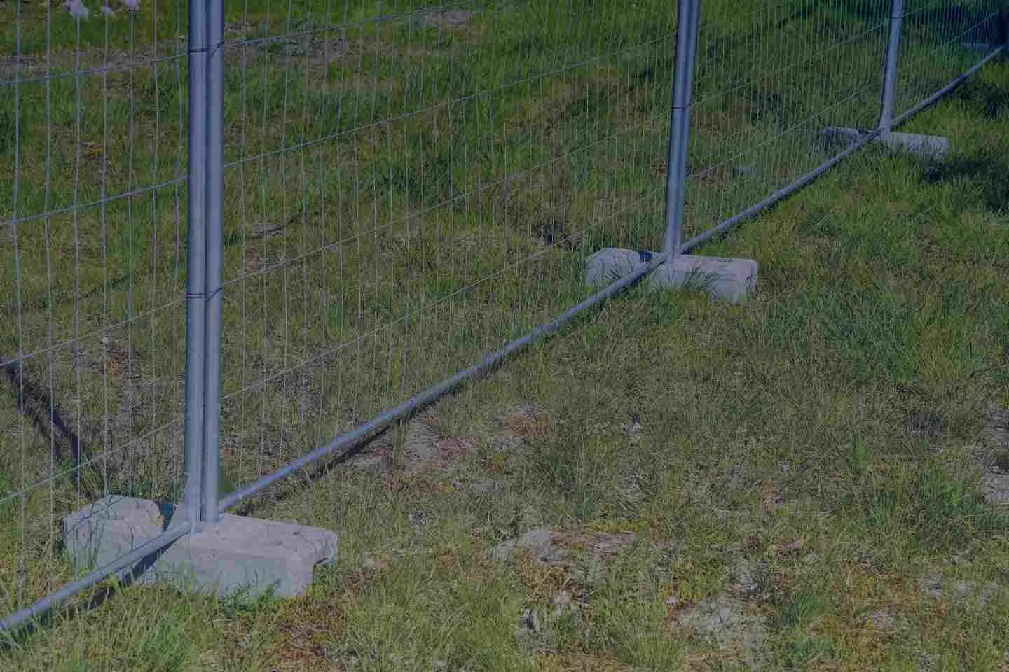temporary fence anchored in concrete blocks on green grass